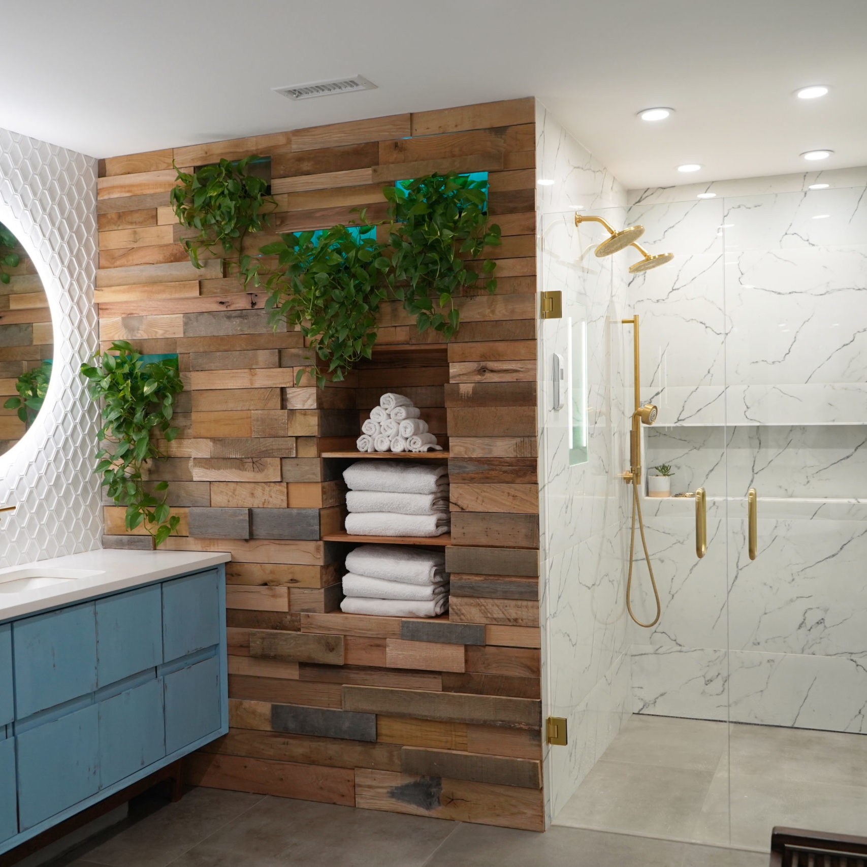 Bathroom Remodel Company in Atlanta with contemporary vanity, marble tile, walk in shower, gold shower, gold faucets, wood wall, white tile, round mirrors.